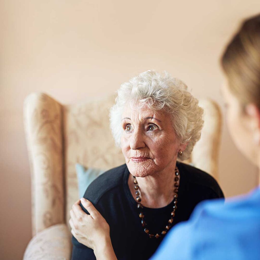 Nurse reviewing medications and appointment notes with an older assisted living resident at a table.