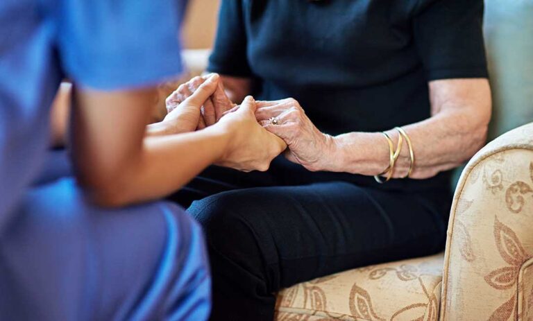 Older resident choosing breakfast while a caregiver reviews a daily routine in a bright dining area.